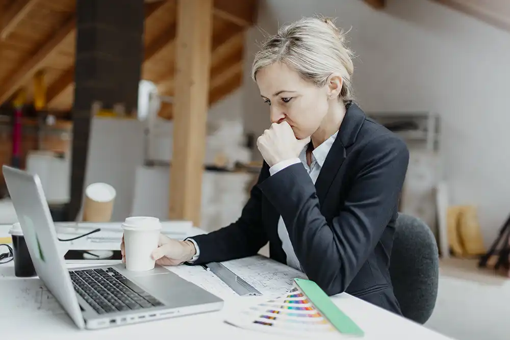 Gondterhelt üzletasszony a laptopján pénzügyi kimutatást néz, a vállalat pénzügyi helyzete bizonytalan – szerkezetátalakítási eljárás előtti döntés